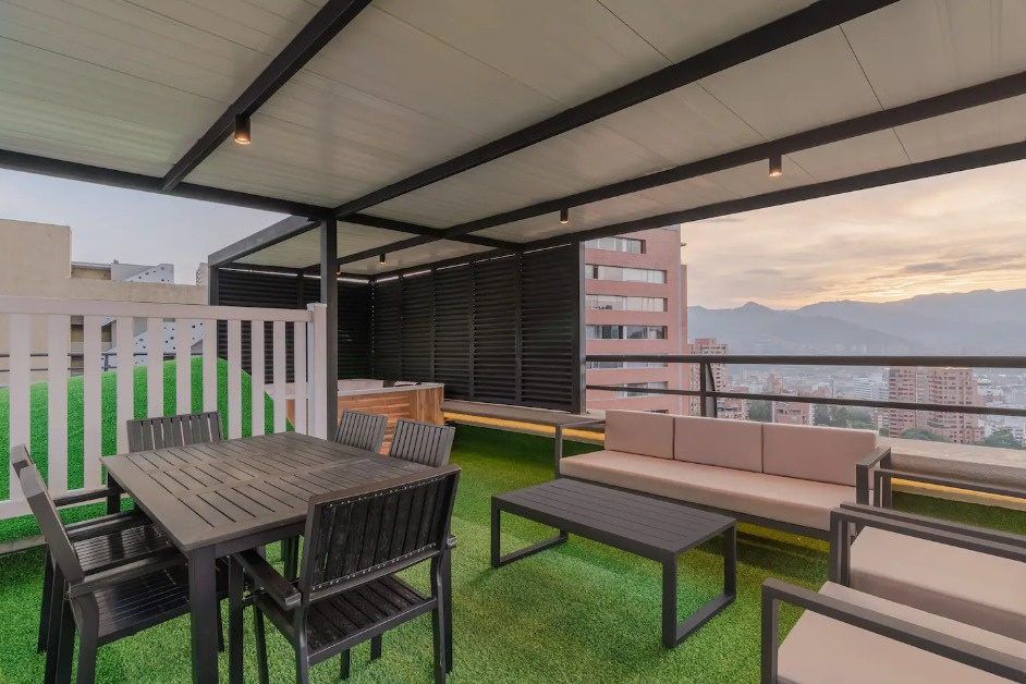 Terraza rooftop con comedor y vista a las montañas al atardecer en el penthouse Ático, Medellín