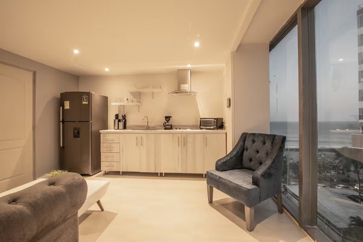 Sala y cocina con ventanales en Boca Grande Loft, Cartagena