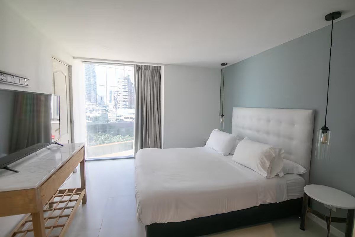 Habitación con cama blanca y vista a la ciudad en Boca Grande Loft, Cartagena