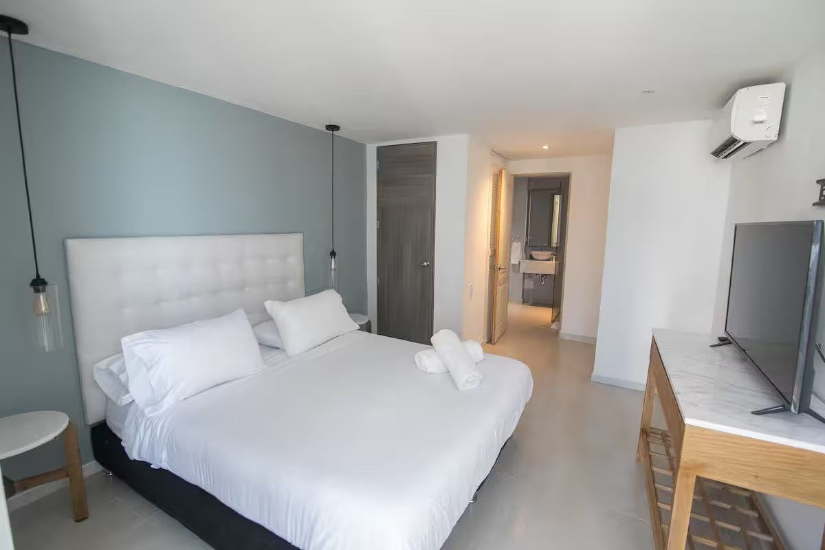 Habitación con cama blanca y TV en Boca Grande Loft, Cartagena