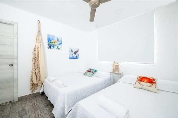 Bedroom with two beds and ceiling fan at House Playa, Cartagena
