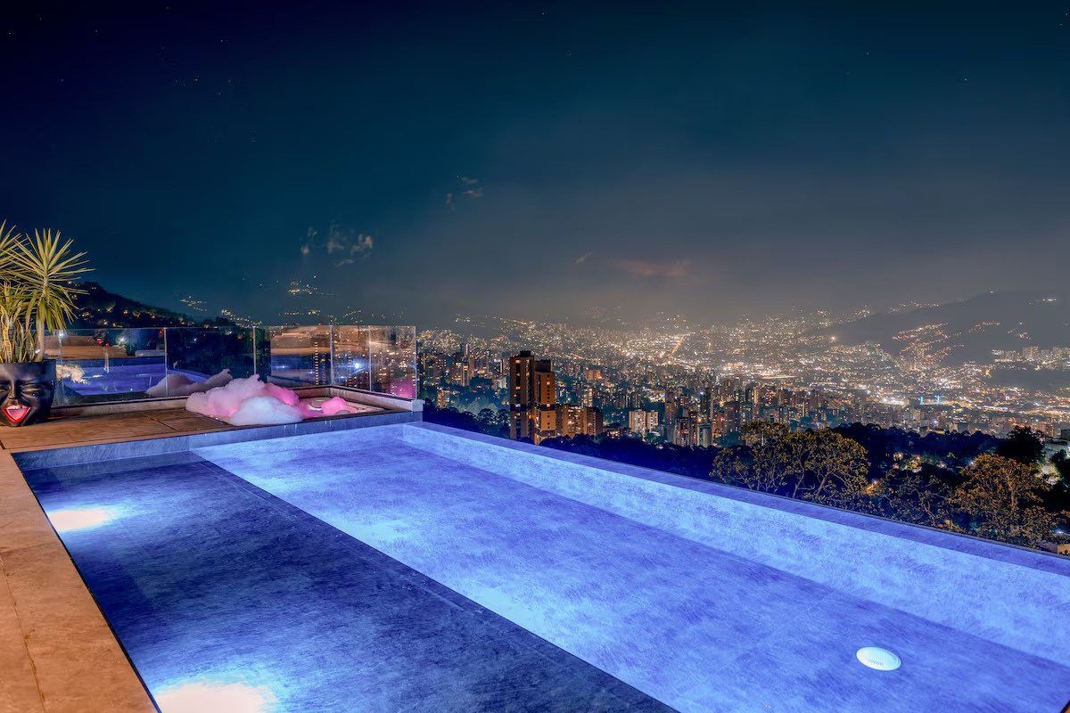 Piscina de noche con las luces de Medellín al fondo, Palmas Royal View