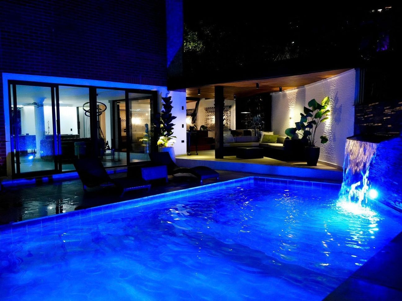 Pool lit at night with waterfall at Pool House, Medellin