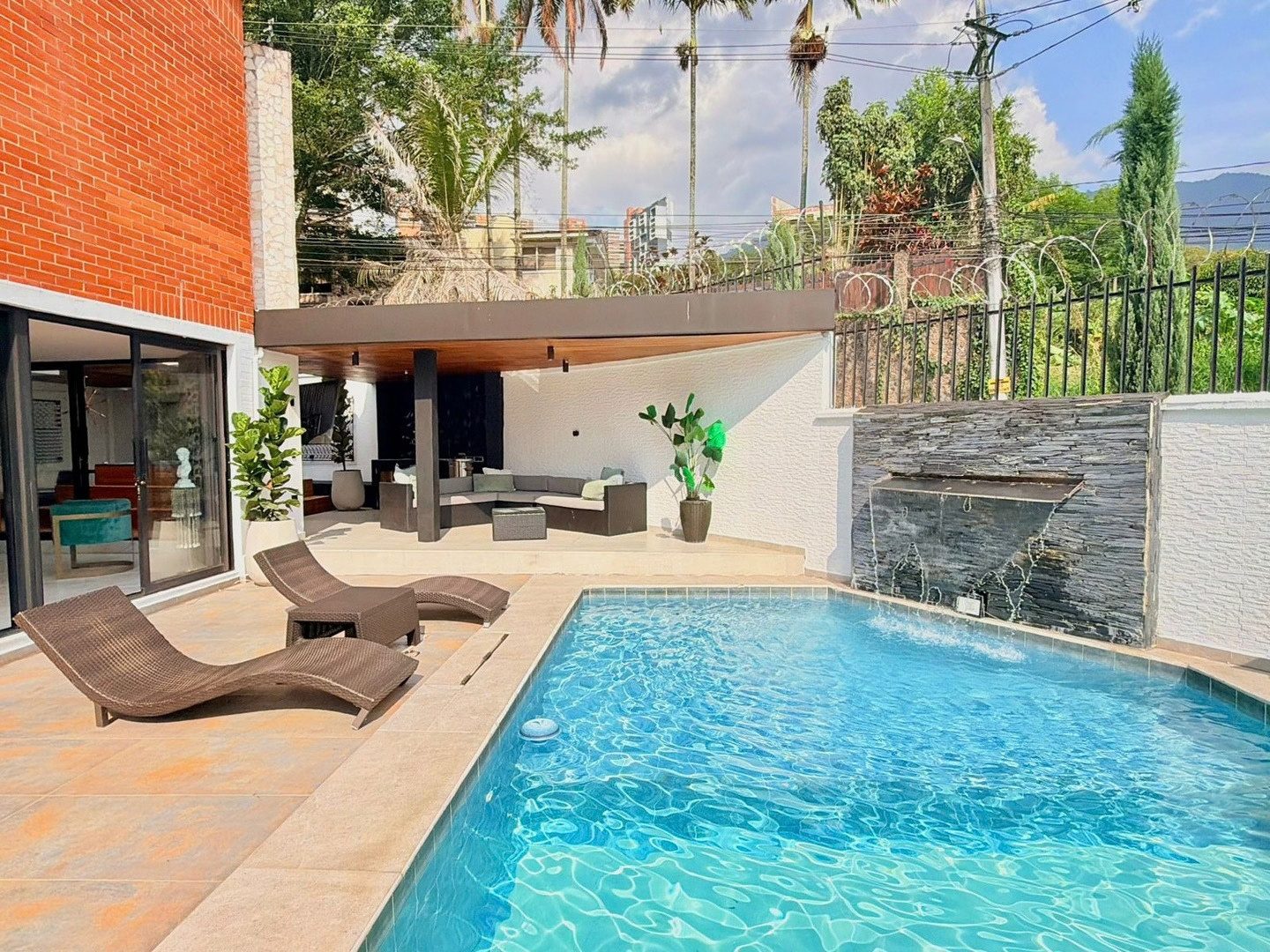 Pool deck with loungers and stone waterfall at Pool House