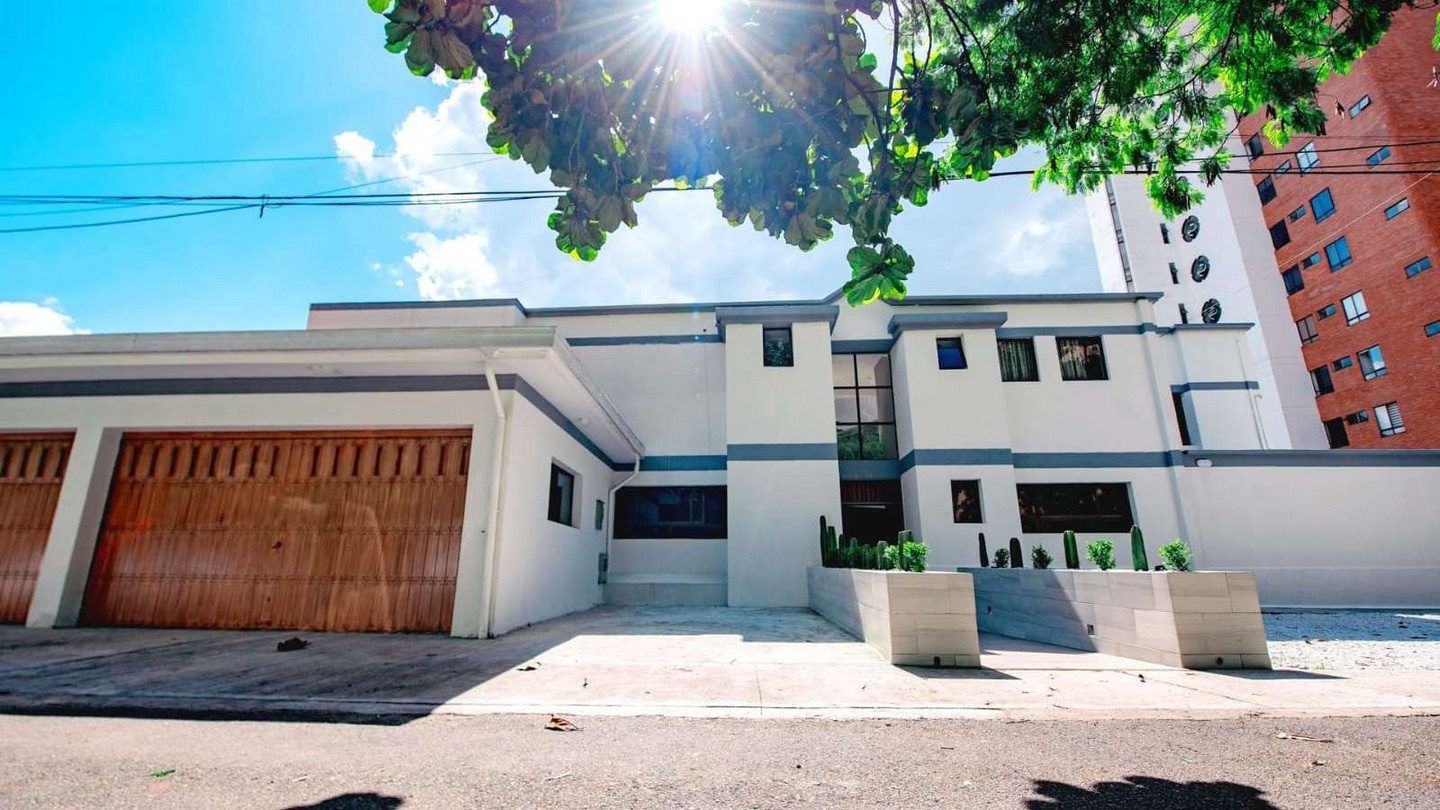 Exterior of White Mansion in Medellin with white facade and wooden garage doors