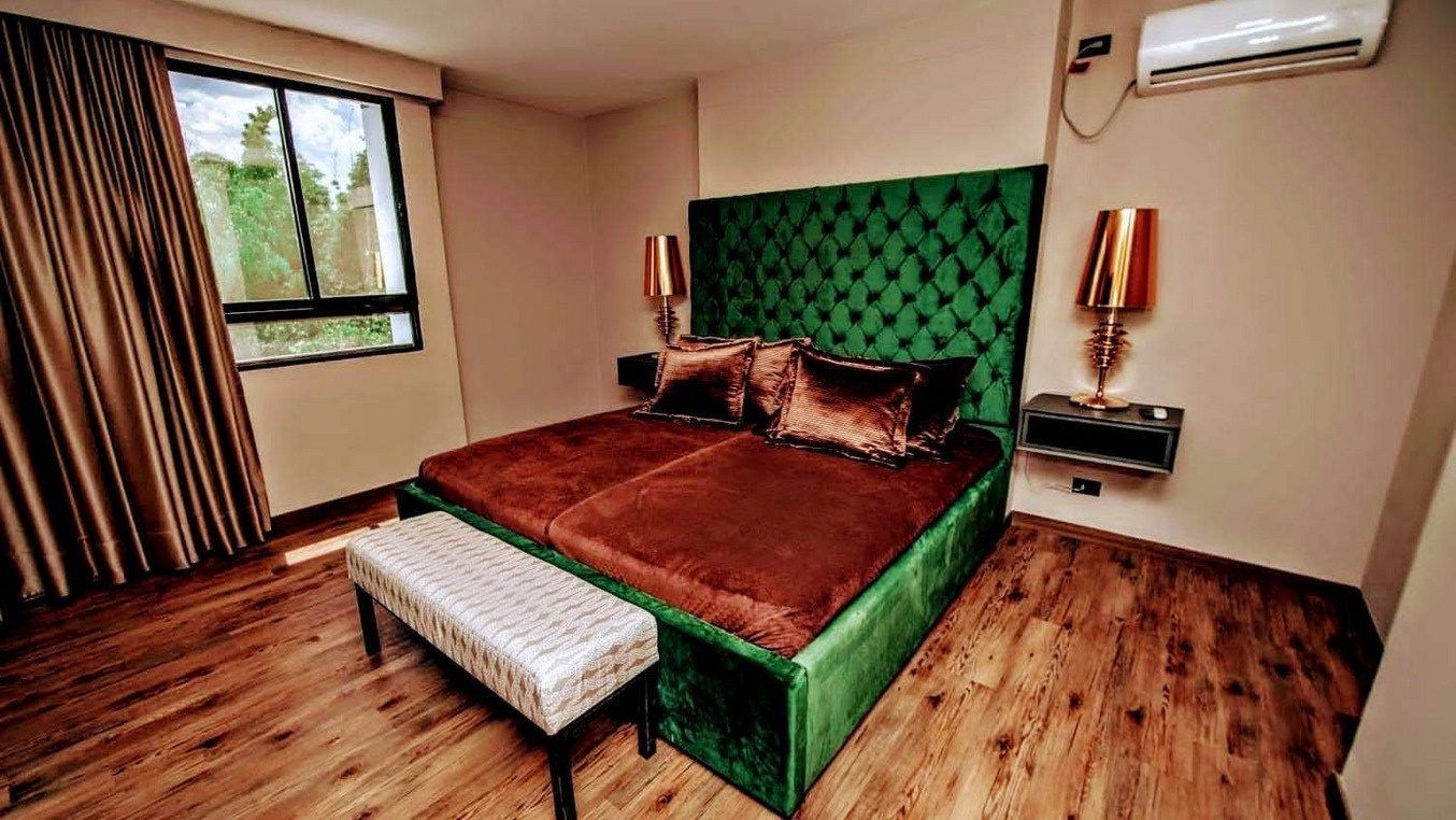 Bedroom with green velvet bed at White Mansion, Medellin
