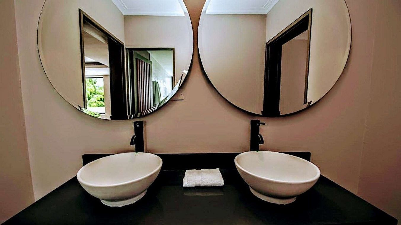 Bathroom with double vanity and round mirrors at White Mansion, Medellin