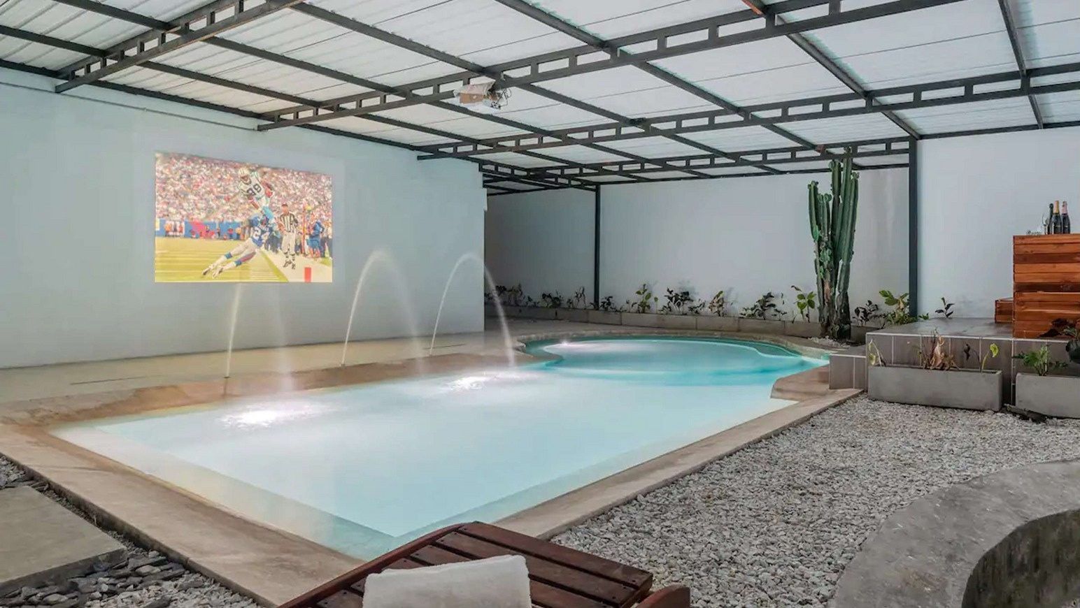 Covered swimming pool with fountains and projection screen at White Mansion, Medellin