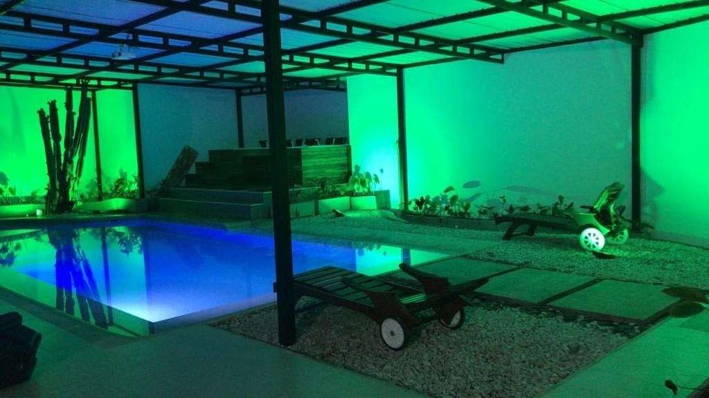 Swimming pool lit in green under a pergola at White Mansion, Medellin