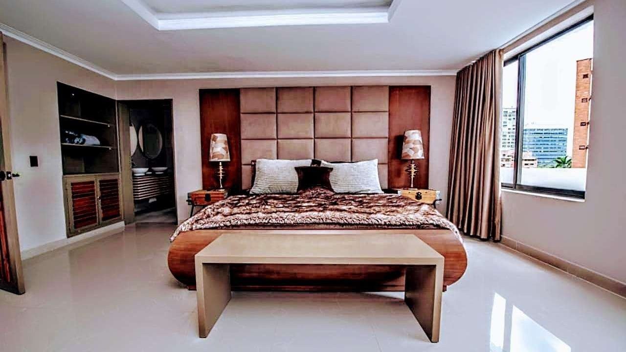 Bedroom with padded wood headboard at White Mansion, Medellin