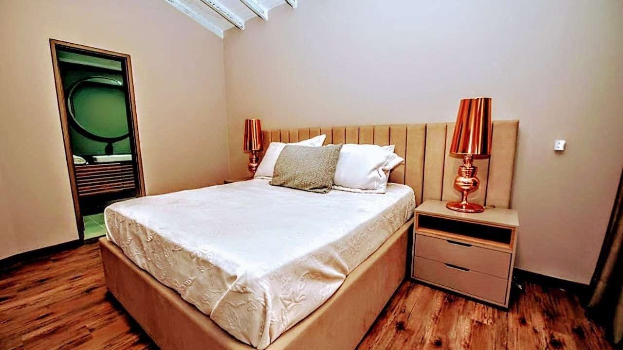 Bedroom with wood floors and cream headboard at White Mansion, Medellin