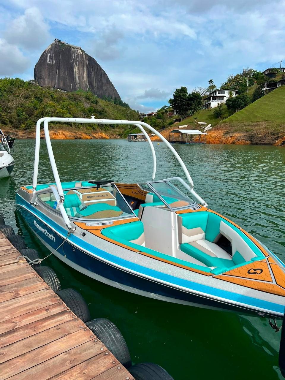 Bote de wakeboard Mastercraft en el muelle de Guatapé con la Piedra del Peñol al fondo