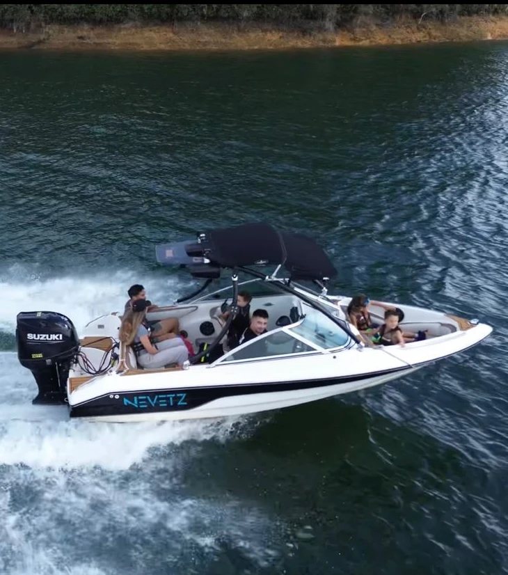 Bote de wakeboard White Nevetz navegando en el embalse de Guatapé con huéspedes a bordo