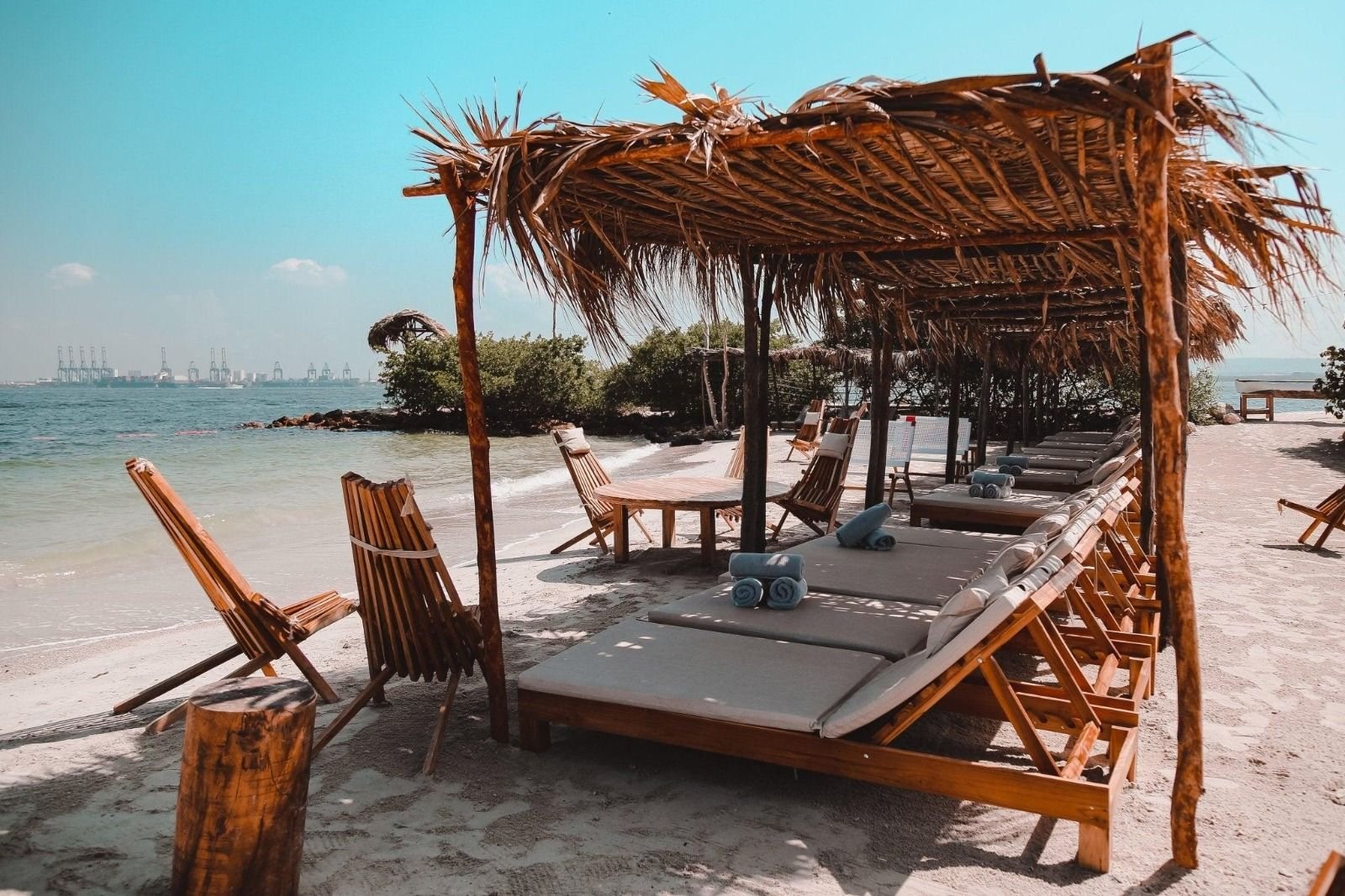 Thatched cabanas with sun loungers and rolled towels on the beach at Fénix Beach, Tierra Bomba, Cartagena