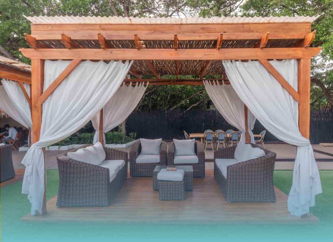 Pergola lounge with white curtains and sofas at Pao Pao Beach Club, Rosario Islands