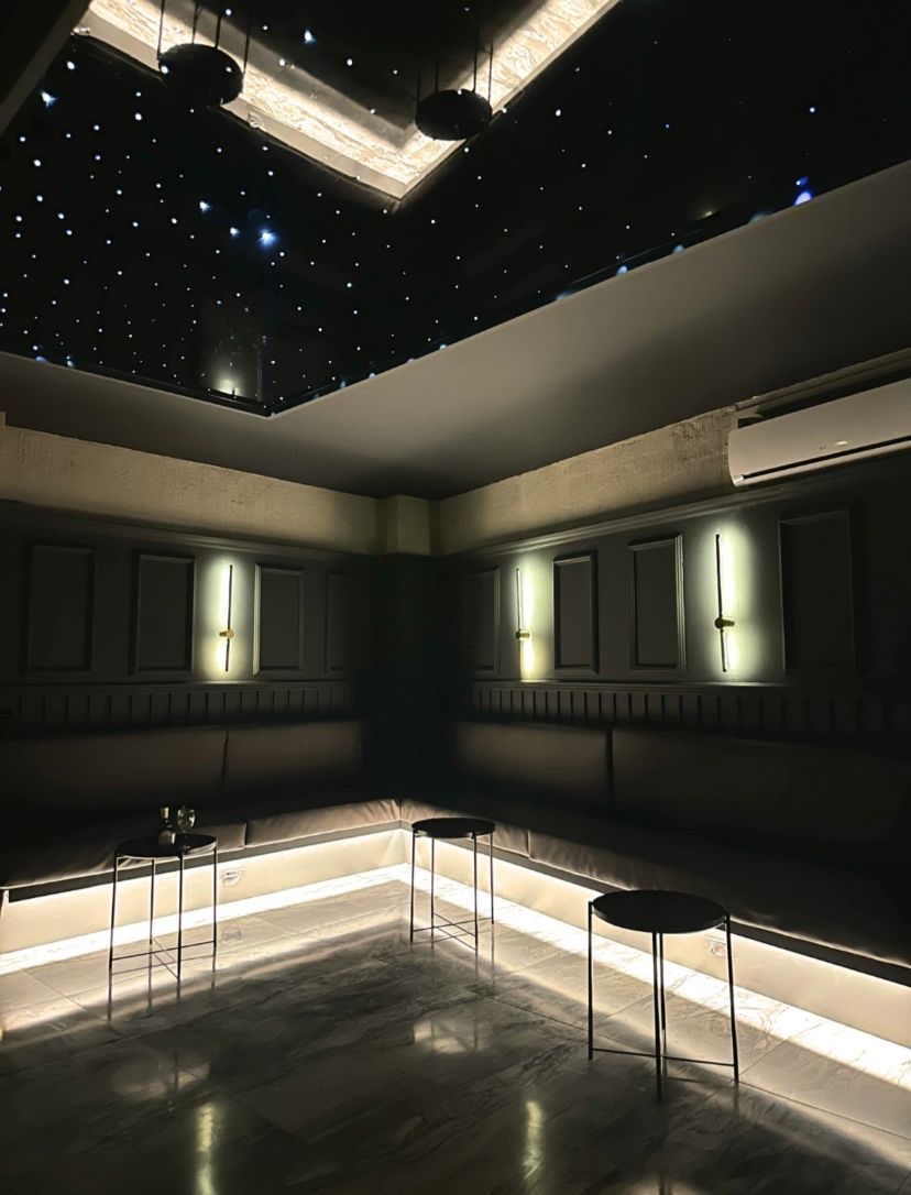 Black Room in Medellín: L-shaped lounge banquette with LED under-lighting and brass wall sconces