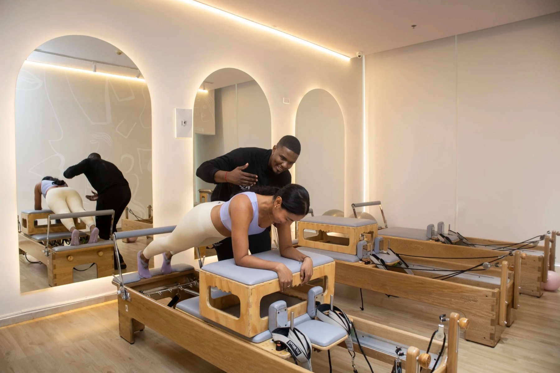 Instructor de pilates corrigiendo una plancha en un estudio boutique